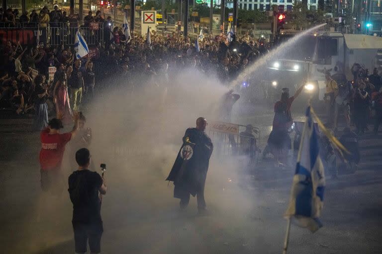 En Tel Aviv la policía utiliza los chorros de camiones hidrantes para dispersar a los manifestantes durante una protesta contra el gobierno del primer ministro israelí, Benjamin Netanyahu, y pidiendo la liberación de rehenes retenidos en la Franja de Gaza por el grupo militante Hamas (AP Photo/Ariel Schalit)