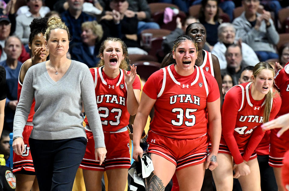 Utah's Matyson Wilke, Alissa Pili and Samantha Crispe celebrates on the bench behind head coach Lynne Roberts during the game against the South Carolina at the Women's Hall of Fame Showcase at Mohegan Sun Arena in Uncasville, Connecticut, on Dec. 10, 2023. (Photo by G Fiume/Getty Images)