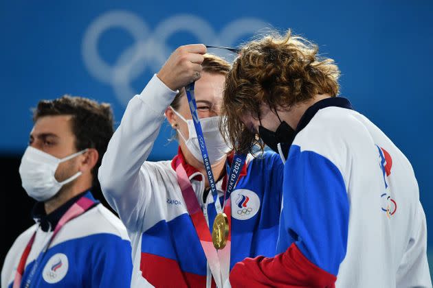 Gold medalists Anastasia Pavlyuchenkova, center, and Andrey Rublev, right, of the Russian Olympic Committee put on their respective medals during the mixed doubles tennis medal ceremony on Aug. 1. (Photo: VINCENZO PINTO via Getty Images)