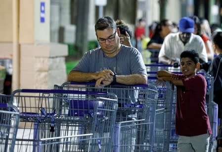 A shopper checks the time while waiting for a Sam's Club store to open before sunrise, as people rushed to buy supplies ahead of the arrival of Hurricane Dorian in Kissimmee