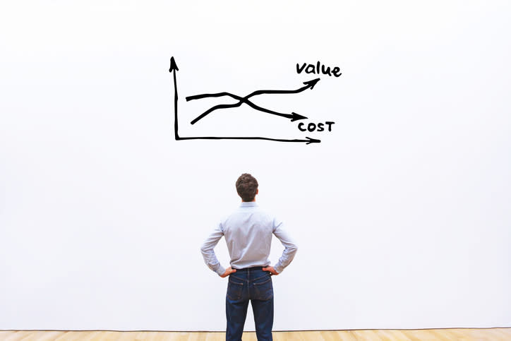 A man staring at a chart of expenses and profits. The chart has two intersecting lines, one labeled value and the other labeled cost.