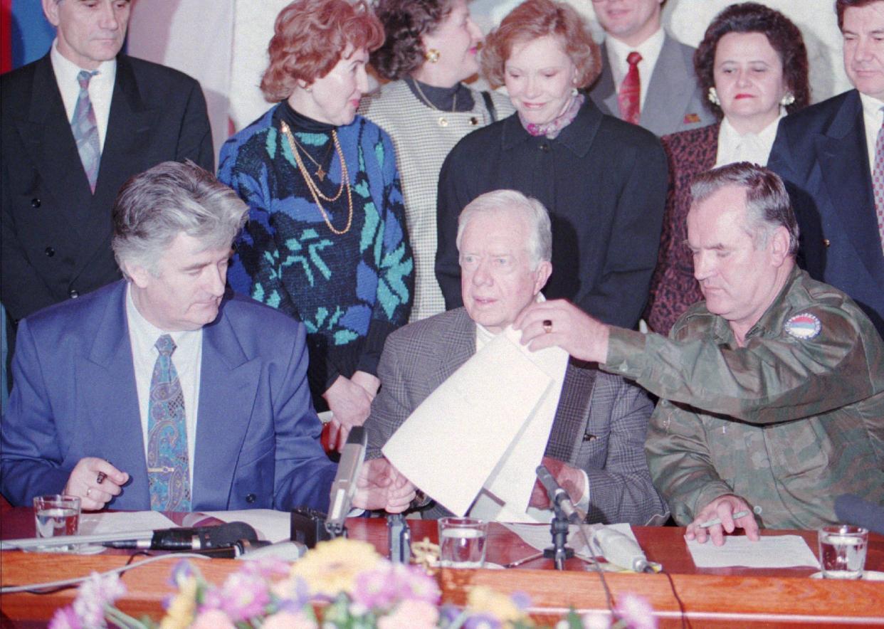 After seven hours of talks at the Bosnian Serb headquarters on Dec.19, 1994, in Pale, Bosnia, former President Jimmy Carter, center, Bosnian Serb leader Radovan Karadzic, left, and Bosnian Serb military commander Ratko Mladic, right, sign a declaration proposing a four-month cease-fire in the Bosnian war. Former President Carter's wife Rosalynn stands behind her husband.