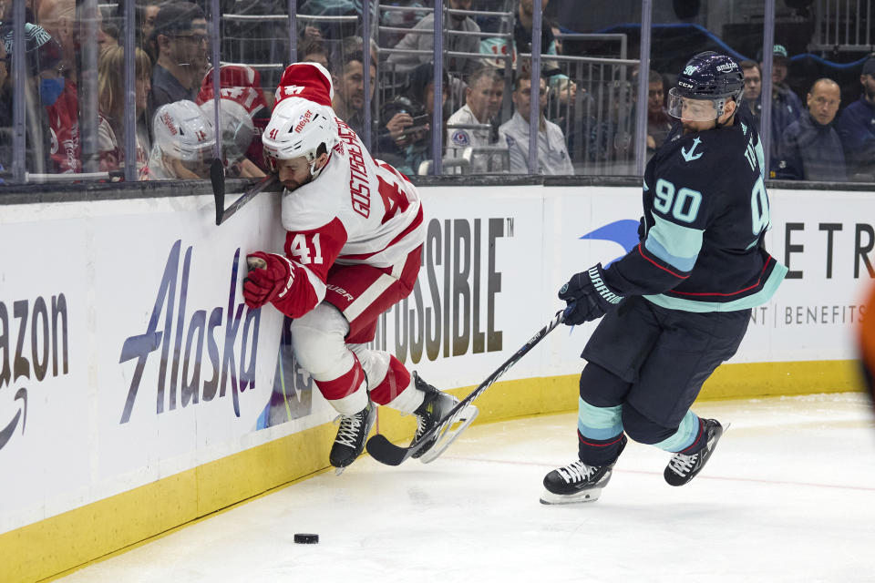 Detroit Red Wings defenseman Shayne Gostisbehere (41) hits the glass while battling for the puck against Seattle Kraken left wing Tomas Tatar (90) during the first period of an NHL hockey game, Monday, Feb. 19, 2024, in Seattle. (AP Photo/John Froschauer)