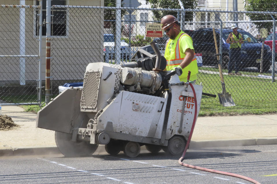 A worker uses an industrial cutting machine to open a section of the street in Ocean City, N.J. on Sept. 12, 2023, at the start of land-based probing along the right-of-way where a power cable for New Jersey's first offshore wind farm is proposed to run. Several protestors were arrested trying to block the work for the project being done by Danish wind energy company Orsted. (AP Photo/Wayne Parry)