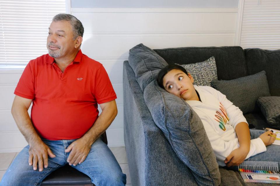 Joaquin Hurtado sits at home with his daughter.