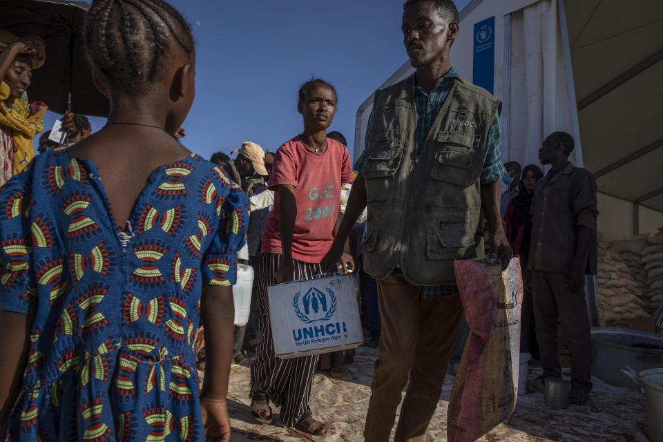 Tigray refugees who fled the conflict in Ethiopia's Tigray region, receive aid from the UNHCR at Umm Rakouba refugee camp in Qadarif, eastern Sudan, Tuesday, Nov. 24, 2020. (AP Photo/Nariman El-Mofty)