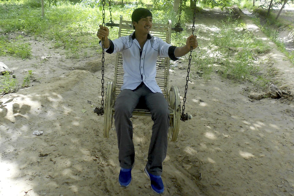 In this photo released by Nursimangul Abdureshid, Uyghur Memetali Abdureshid sits on a swing in Hotan in China's far west Xinjiang region in July 2013. Nearly one in 25 people in a county in the Uyghur heartland of China has been sentenced to prison on terrorism-related charges, in what is the highest known imprisonment rate in the world, an Associated Press review of leaked data shows. Abdureshid, who ran a car repair shop, was listed as being sentenced to 15 years and 11 months in prison on charges of "picking quarrels and provoking trouble” and “preparing to carry out terrorist activities." (Nursimangul Abdureshid via AP)