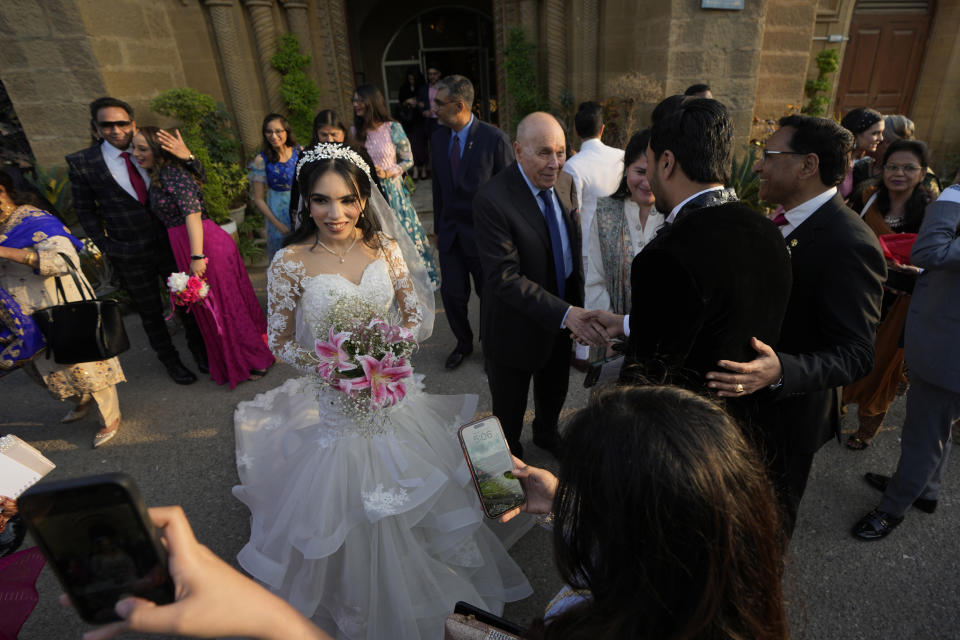 Pakistani Christian groom Sharoon Arjumand John, third left, and his bride Yamima Teresa Bhagtaney, center, receive wedding greetings from family and friends after their wedding ceremony at Holy Trinity Cathedral in Karachi, Pakistan, Saturday, Jan. 27, 2024. Pakistan's winter months are all about weddings. The cooler temperatures between November and February see millions of people attending festivities every week. The wedding season has become a calendar fixture, like birthdays. It even has a nickname, Decemberistan. (AP Photo/Fareed Khan)