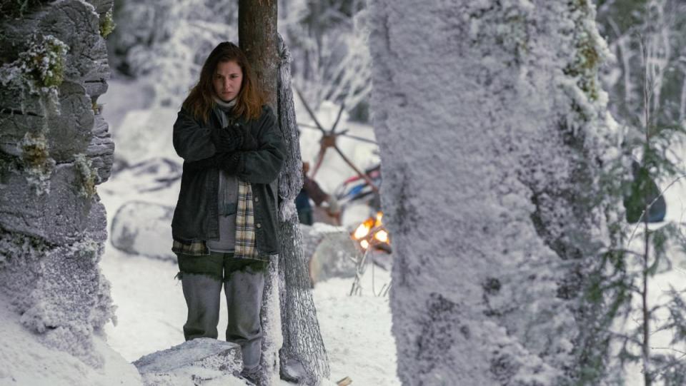 Shauna stands in the snowy wildnerness near a tree in Yellowjackets while pregnant with her baby