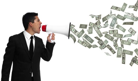 Businessman yelling into megaphone with money coming out of it.