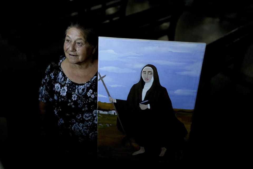 Rita Canteros poses for a picture alongside a painting depicting María Antonia de Paz y Figueroa, more commonly known by her Quechua name of “Mama Antula,” on the outskirts of Buenos Aires, Argentina, Sunday, Jan. 28, 2024. The canonization of “Mama Antula” in a Feb. 11th ceremony to be presided by Pope Francis at St. Peter's Basilica marks the first time a female from Argentina will become saint. (AP Photo/Natacha Pisarenko)