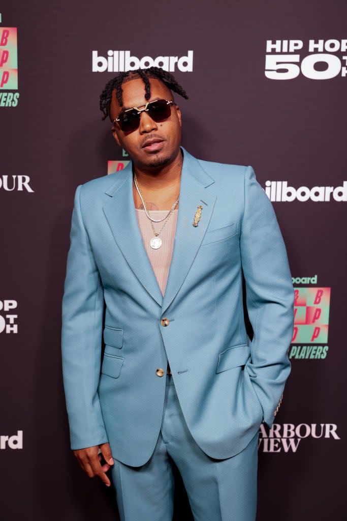 Man in a light blue suit with sunglasses and gold jewelry at the Billboard event
