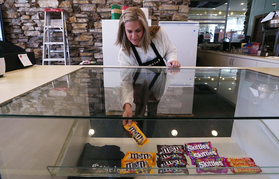 Melissa Sly, president of the Camelot Theater Foundation, stocks concessions at the historic theater in downtown Nevada, Iowa.