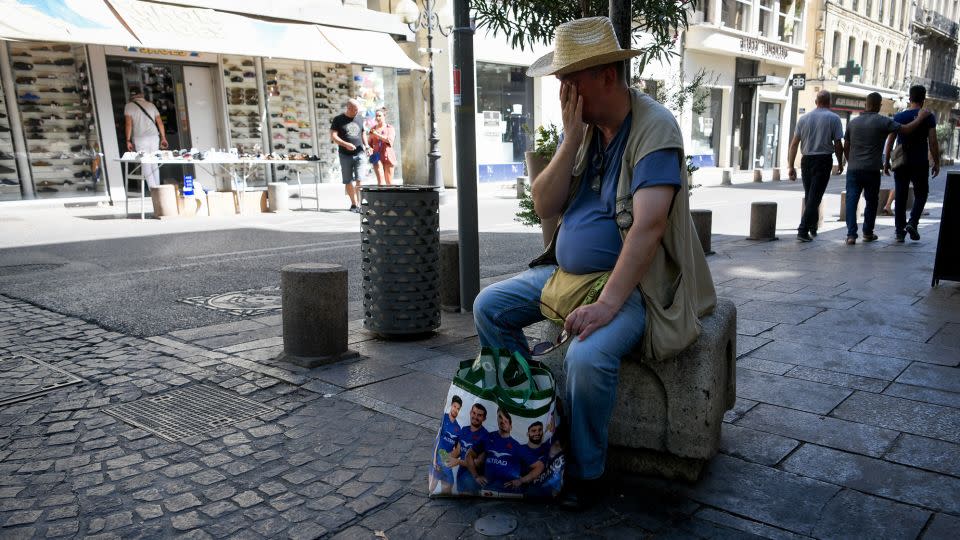 A man wipes off sweat and rests during a heatwave. Météo-France has issued red-level heat alerts for four departments in France. - Igor Ferreira/SOPA Images/LightRocket/Getty Images