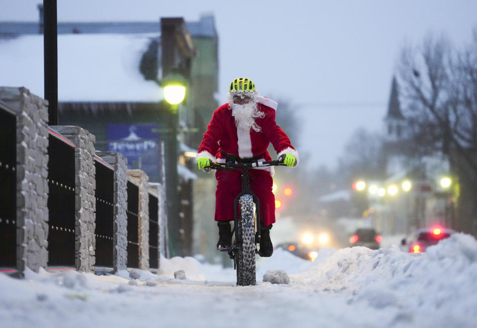Brian Dickie, dressed as Santa Claus, rides his bike through the wintery streets of Carleton Place, Ontario, Christmas Eve, Saturday, Dec. 24, 2022. A major winter storm system continues to affect eastern Ontario. (Sean Kilpatrick/The Canadian Press via AP)