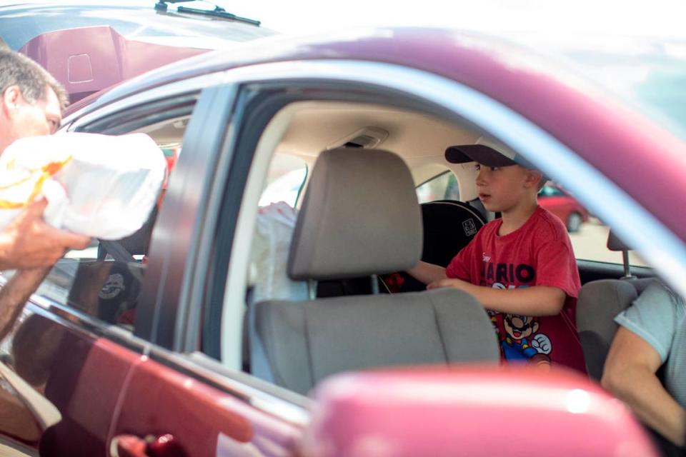 Tomas Preece receives bags of toys and games through the car window from staff with the Christian Appalachian Project during a toy giveaway event held at Lawrence County High School in Louisa, Ky., Thursday, June 24, 2021.