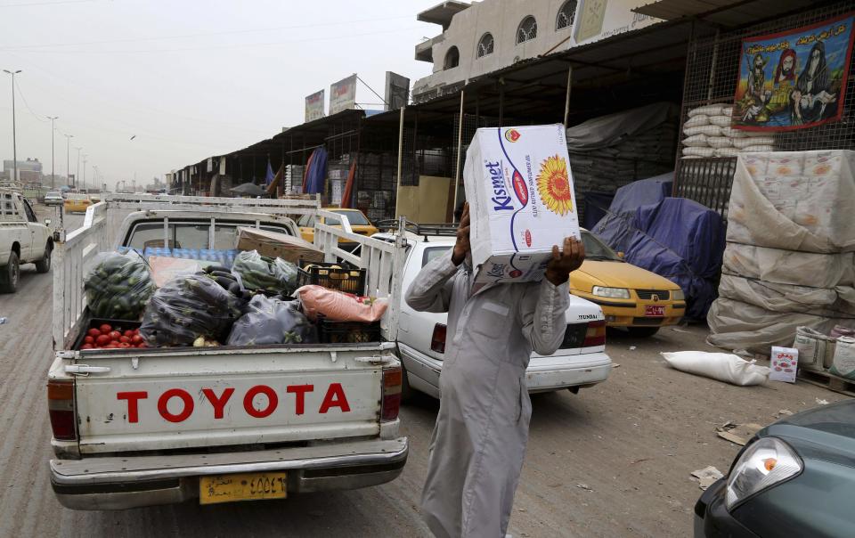 In this photo taken on Friday, May 9, 2014 a man carries goods at a food market in Jamila, Baghdad, Iraq. Fighting in Iraq’s western Anbar province, now in its fifth month, appears to have bogged down, with government forces unable to drive out Islamic militants who took over one of the area’s main cities. But the impact is being felt much further, with the repercussions rippling through the country’s economy to hit consumers and businesses. Fighting has also disrupted shipping, inflating prices of goods in Baghdad and elsewhere. (AP Photo/ Karim Kadim)