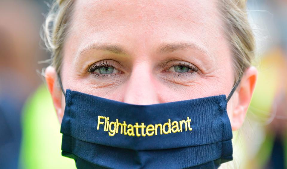 A flight attendant wears a face mask as employees of German flight operator Lufthansa demonstrate on June 24, 2020 in Berlin, in order to call on investors to back a bailout plan hammered out to rescue the airline hit by the coronavirus crisis. (Photo by TOBIAS SCHWARZ/AFP via Getty Images)