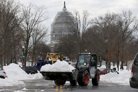 Workers use heavy machinery to remove snow from a parking area at the U.S. Capitol in Washington January 26, 2016. REUTERS/Jonathan Ernst