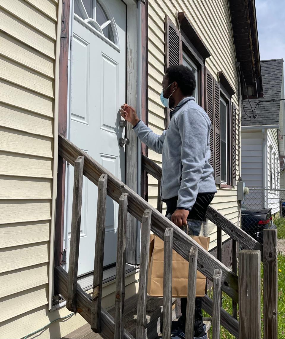 Olu Owoyele knocks on a door to deliver groceries for PLP Rochester's Free Grocery Program.