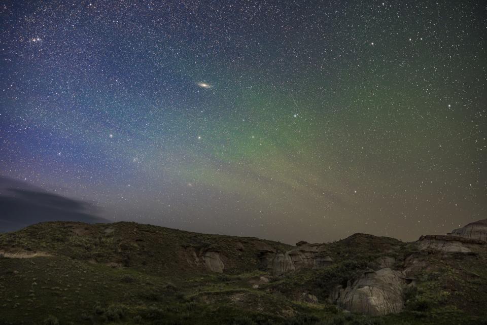 a white wispy disk can be seen among the stars of the night sky