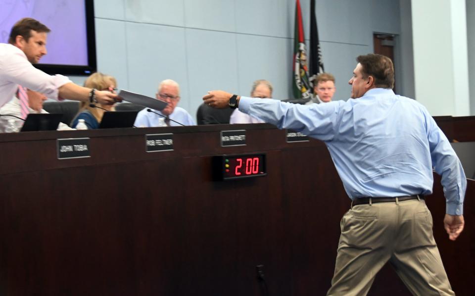Commissioner John Tobia hands information about sample ballots that he researched to Supervisor of Elections Tim Bobanic, as he was about to address the commission at the Sept. 19, 2023, final budget meeting of the Brevard County Board of County Commissioners.