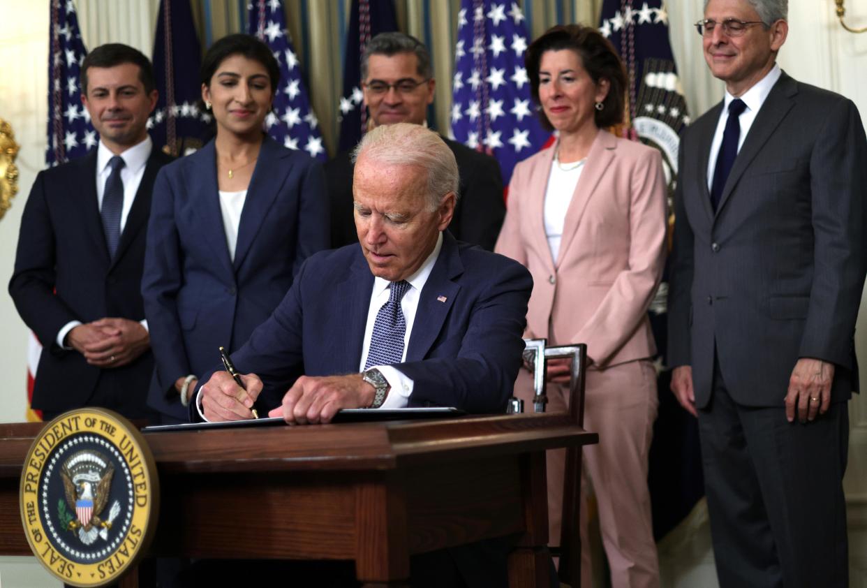 President Biden signs an executive order on Friday as (left to right) Secretary of Transportation Pete Buttigieg, Chairperson of the Federal Trade Commission Lina Khan, Secretary of Health and Human Services Xavier Becerra, Secretary of Commerce Gina Raimondo, and Attorney General Merrick Garland look on.