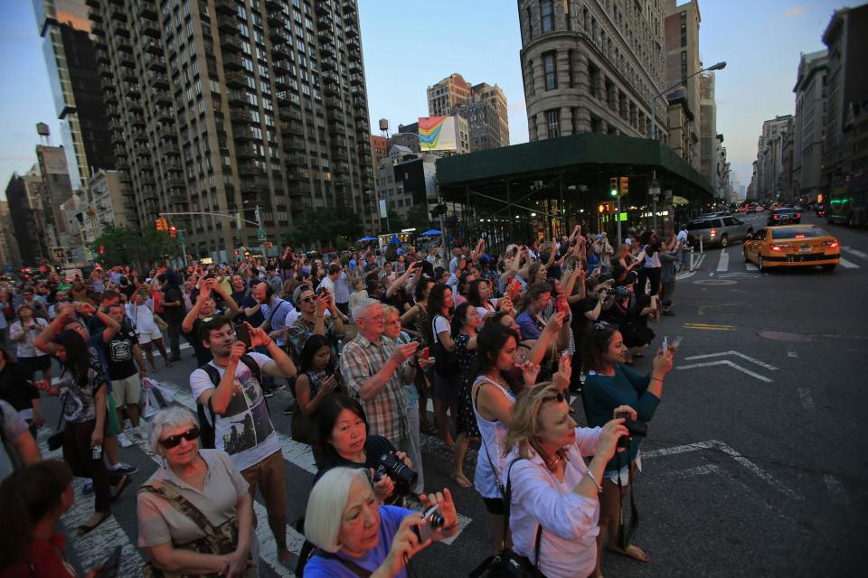 People take pictures at sunset, during the bi-annual occurrence "Manhattanhenge" in New York