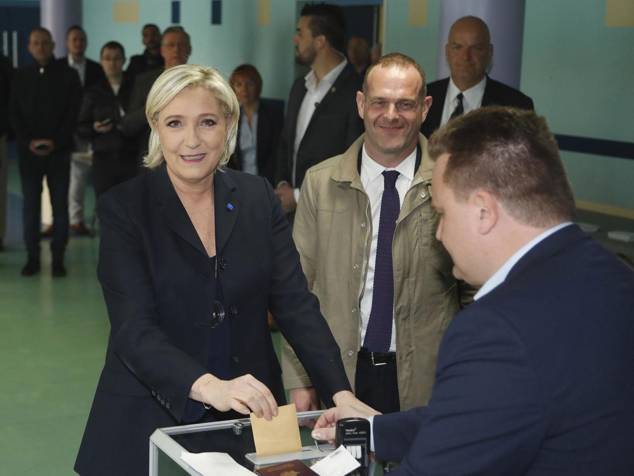 Louis Aliot (c) looks on from behind as presidential candidate and then-Front National leader Marine Le Pen casts her vote in the first round of the election