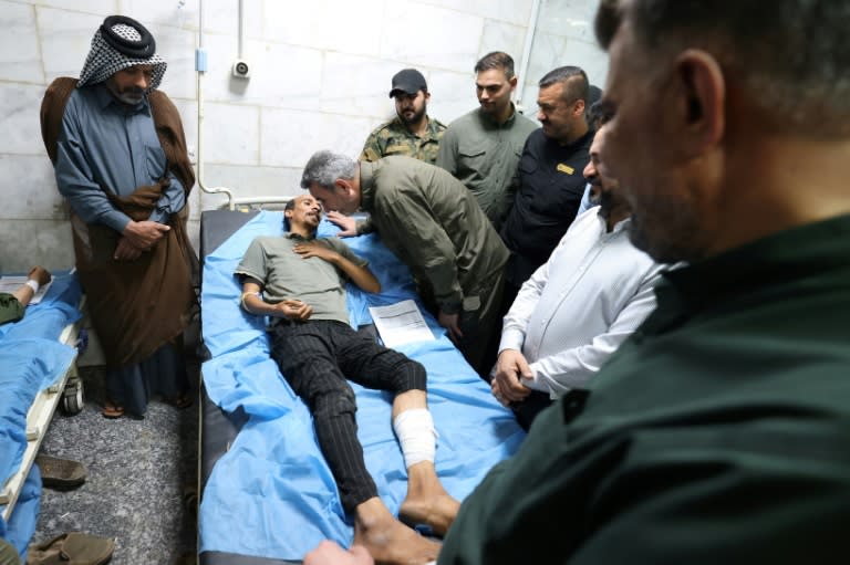 Abu Fadak Al-Mohammedawi (C-R), the chief of staff of Iraq's Popular Mobilisation Forces, visits a man at a hospital in Hilla in the central province of Babylon after he was wounded in an explosion overnight (Karar Jabbar)