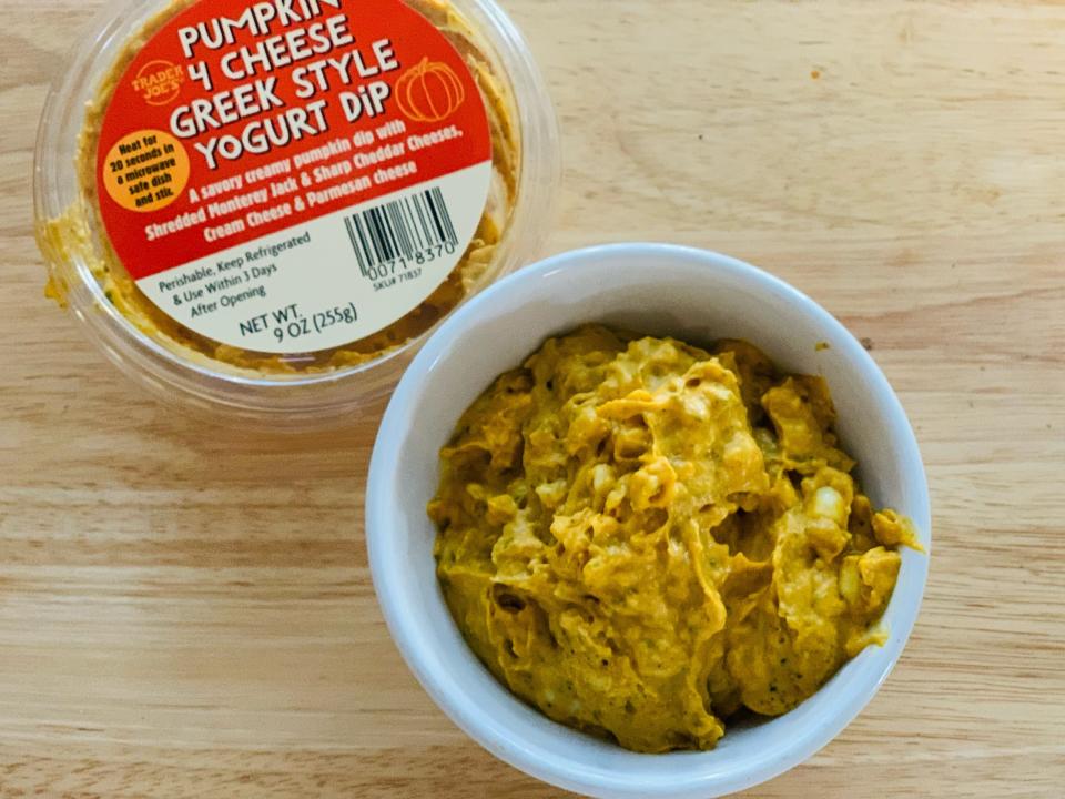 Container of Trader Joe's pumpkin greek yogurt cheese dip alongside a bowl of it on a wooden table