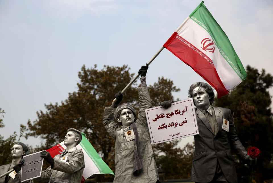 FILE - In this Nov. 4, 2013, file photo, Iranian artists hold posters in Farsi reading, "America cannot do a damn thing" as they perform during an annual anti-American demonstration in Tehran, Iran. (AP Photo/Ebrahim Noroozi, File)