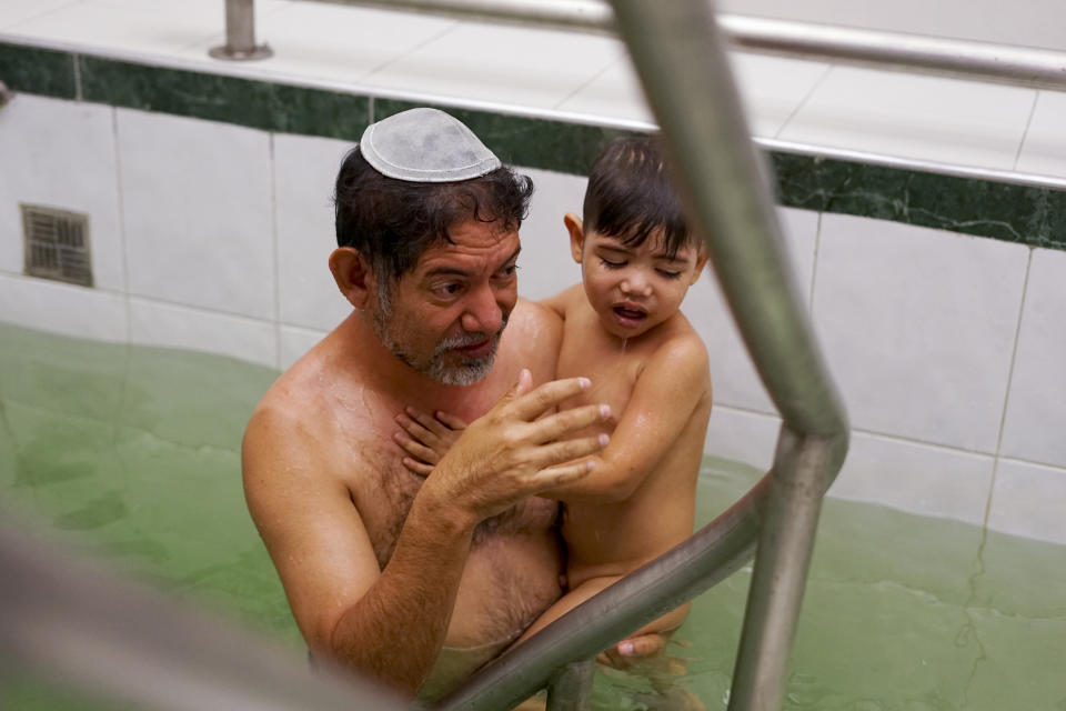 En esta imagen, tomada el 19 de marzo de 2017, Franklin Pérez sumerge a su hijo en un baño especial que marca su conversión al judaísmo, en Bogotá, Colombia. Franklin Pérez y su hijo formar parte de un grupo de nueve venezolanos que completaron un tortuoso viaje a Israel. El grupo se convirtió por segunda vez en otros tantos años con una inmersión ritual como parte de un acuerdo entre legisladores progresistas israelíes y autoridades ultraortodoxas y rabinos que inicialmente rechazaron su petición para inmigrar alegando que no podían demostrar su compromiso con el judaísmo. (AP Foto/Christine Armario)