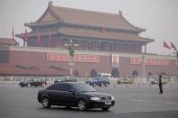 An Audi car drives past Tiananmen Square as a police officer stands guard on a street in central Beijing February 29, 2012.