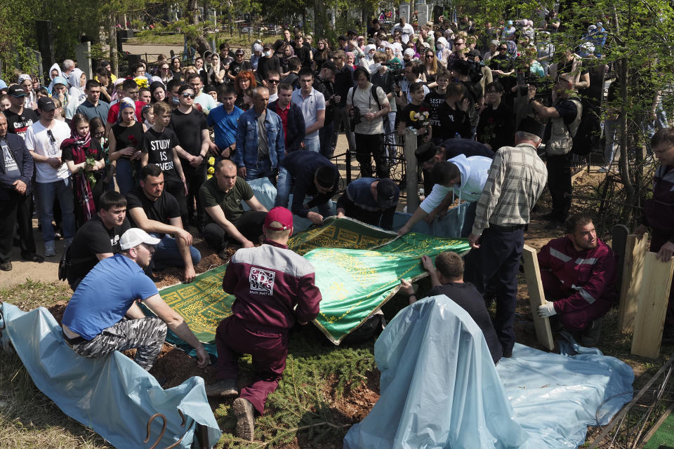 People gather next to the grave during a funeral of Elvira Ignatieva, an English language teacher who was killed at a school shooting on Tuesday, in Kazan, Russia, Wednesday, May 12, 2021. Russian officials say a gunman attacked a school in the city of Kazan and Russian officials say several people have been killed. Officials said the dead in Tuesday's shooting include students, a teacher and a school worker. Authorities also say over 20 others have been hospitalised with wounds. (AP Photo/Dmitri Lovetsky)