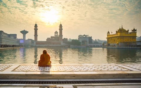 A woman praying outside The Golden Temple - Credit: getty