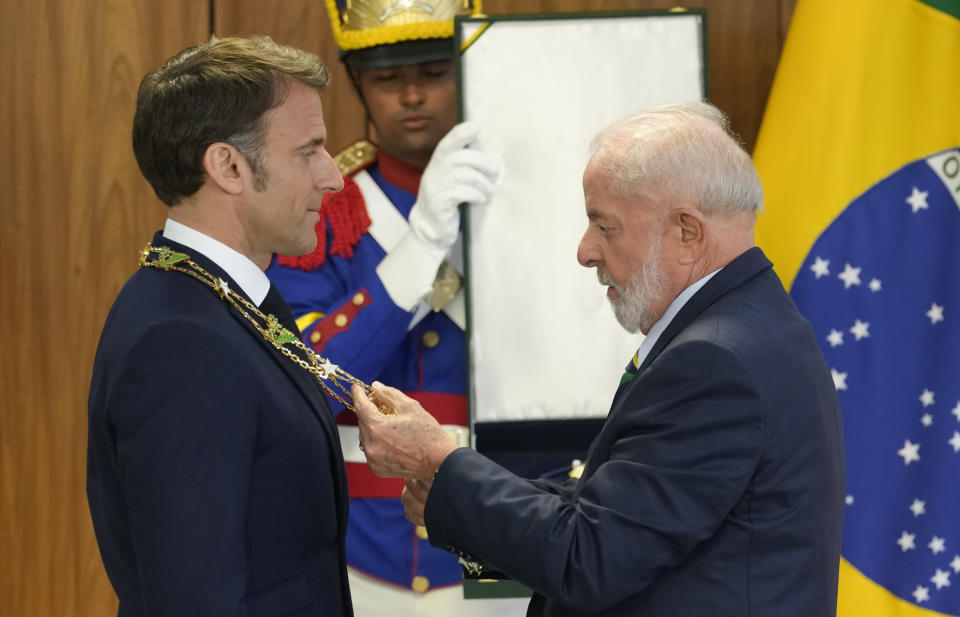 El presidente brasileño Luiz Inácio Lula da Silva honra a su homólogo francés Emmanuel Macron con la medalla "Gran Cruz Cruzeiro do Sul" en el palacio presidencial de Planalto, el jueves 28 de marzo de 2024, en Brasilia, Brasil. (AP Foto/Eraldo Peres)