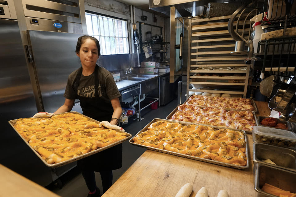 Sandra Castillo removes pretzels from the oven at Von Elrod's Beer Hall And Kitchen on June 7, 2022, in Nashville, Tenn. For the restaurant, located across the street from Nashville's minor league baseball stadium that sees big crowds in the summer, both inflation and the worker shortage have sent costs skyrocketing. Small businesses that depend on summer crowds and tourism are hoping for a bustling summer this year, boosted by pent up demand after more than two years of the pandemic. (AP Photo/Mark Humphrey)