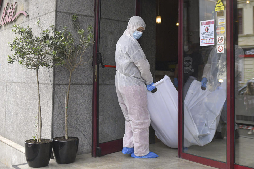 Forensic workers remove a body from a hotel downtown Bucharest, Romania, Friday, June 19, 2020. Gholamreza Mansouri, a former judge from Iran sought by his country to face corruption charges has died in unusual circumstances, Romanian media reported. Romanian police said only that a man had fallen from a high floor at a hotel in Bucharest, the Romanian capital, and was found dead. (AP Photo/Andreea Alexandru)