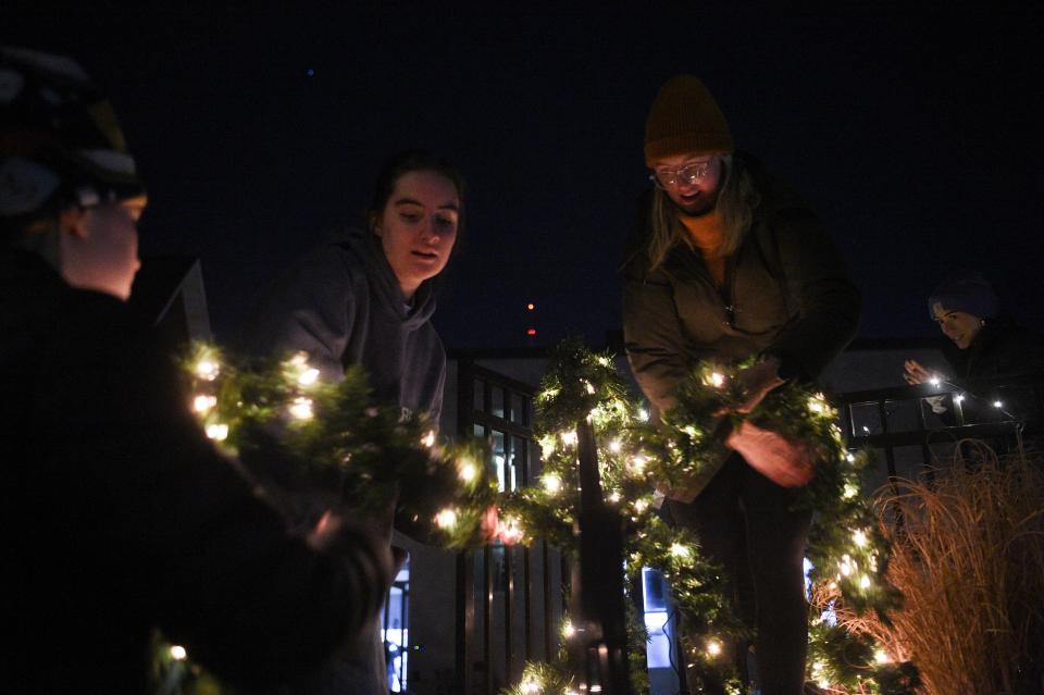 Youth from Redeemer Church of Knoxville assist in decorating a railing at Light Up Lonsdale, put on by Thrive in Lonsdale, Wednesday, Nov. 29, 2023.