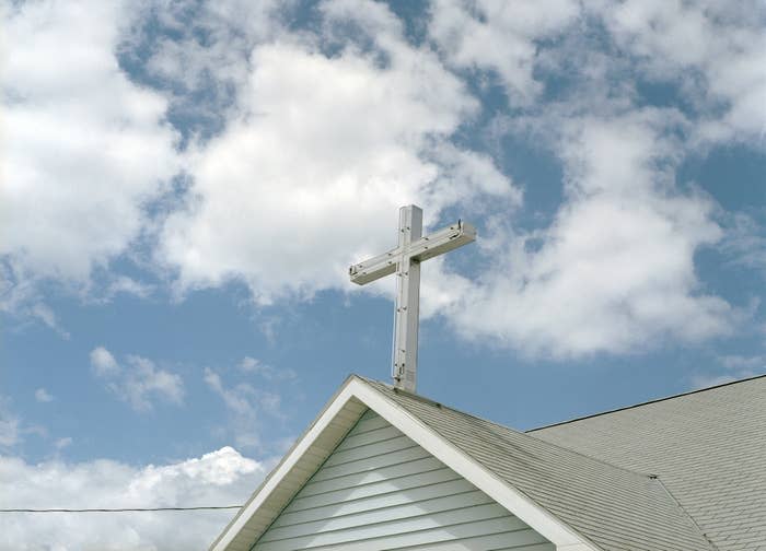 Church roof with cross against a cloudy sky