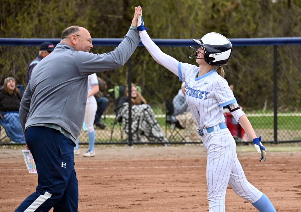 Petoskey assistant coach Dave Hansen (left) and Harper Witthoeft celebrate at first base after a hit by Witthoeft.