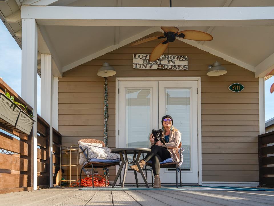 Powers and her dog sit in front of their tiny home