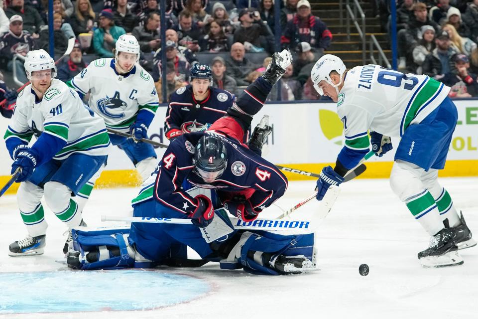 Jan 15, 2024; Columbus, Ohio, USA; Columbus Blue Jackets center Cole Sillinger (4) topples over Vancouver Canucks goaltender Casey DeSmith (29) during the third period of the NHL hockey game at Nationwide Arena. The Blue Jackets won 4-3 in a shootout.