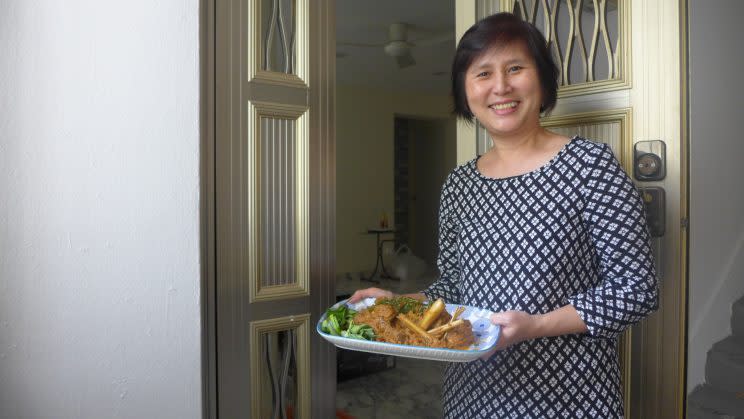 Home cook Josephine Goh carrying a plate of chicken rendang at her doorstep. (Yahoo Lifestyle Singapore)