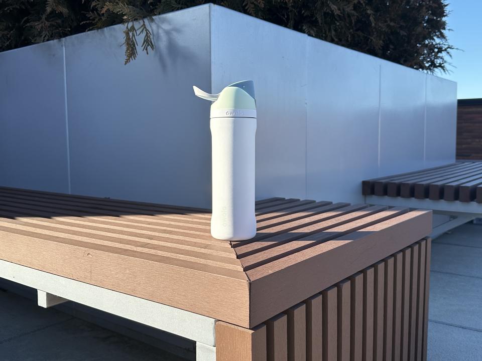 White Owala water bottle on a bench.
