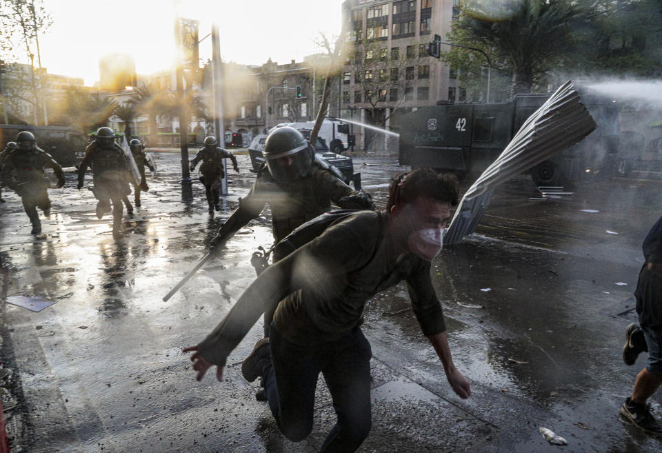 A demonstrator runs away from police during clashes at a protest against police in reaction to a video that appears to show an officer pushing a youth off a bridge the previous day at a protest, in Santiago, Chile, Saturday, Oct. 3, 2020. (AP Photo/Esteban Felix)