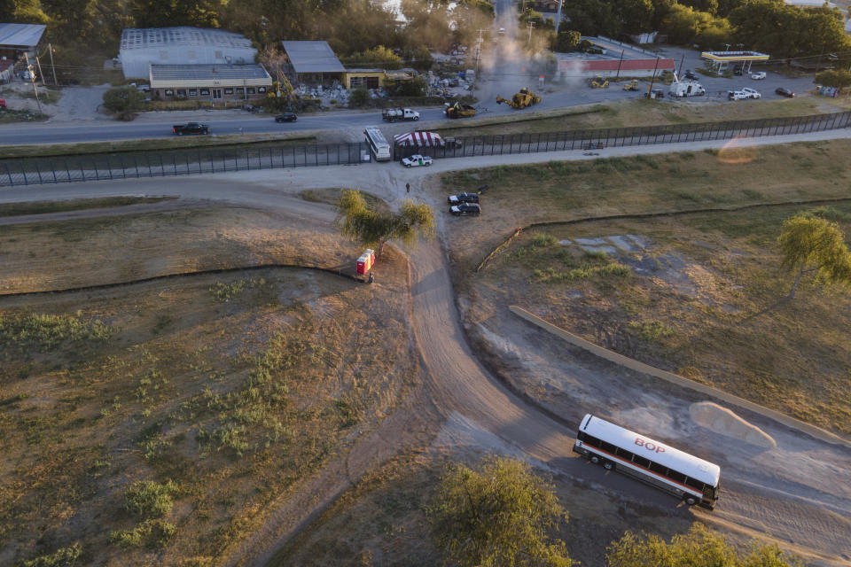 A bus, top center, leaves an area near a migrant encampment along the Del Rio International Bridge as another bus, bottom right, arrives, Thursday, Sept. 23, 2021, in Del Rio, Texas. (AP Photo/Julio Cortez)
