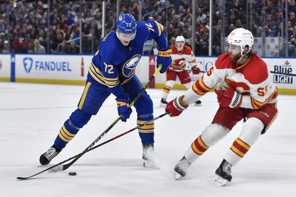 Buffalo Sabres center Tage Thompson, left, looks to shoot as Calgary Flames defenseman Noah Hanifin defends during the second period of an NHL hockey game in Buffalo, N.Y., Saturday, Feb. 11, 2023. (AP Photo/Adrian Kraus)