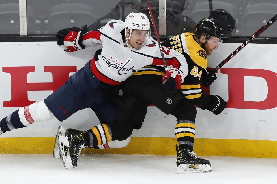 Washington Capitals' Garnet Hathaway (21) and Boston Bruins' Steve Kampfer (44) battle along the boards during the first period of an NHL hockey game, Sunday, April 18, 2021, in Boston. (AP Photo/Michael Dwyer)